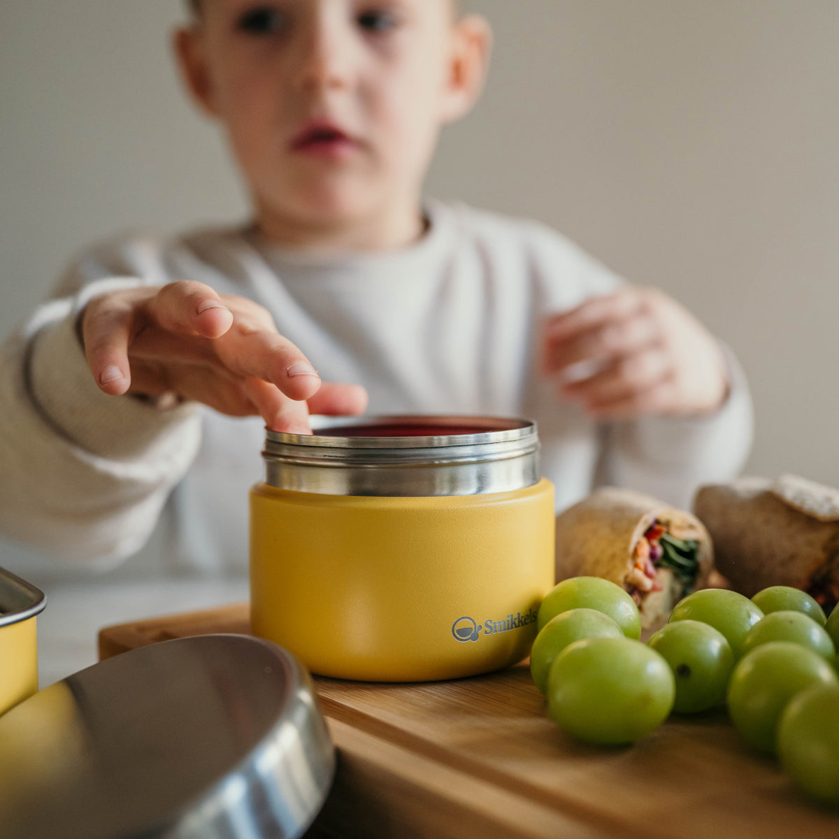 Jongetje stopt iets in geel RVS fruitbakjes van Smikkels