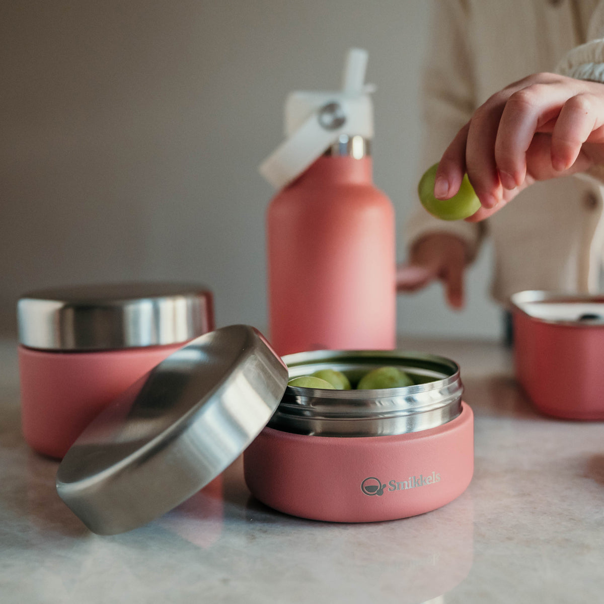 Roze RVS Fruitbakjes van Smikkels met drinkfles op de achtergrond