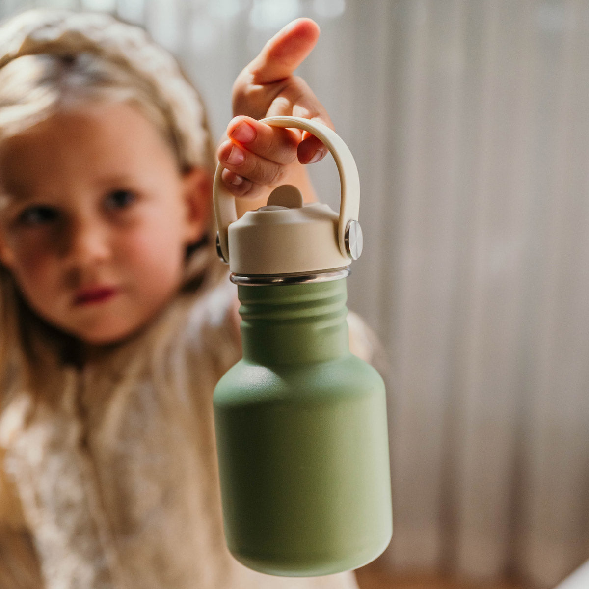 Meisje houdt groene Smikkels drinkfles omhoog
