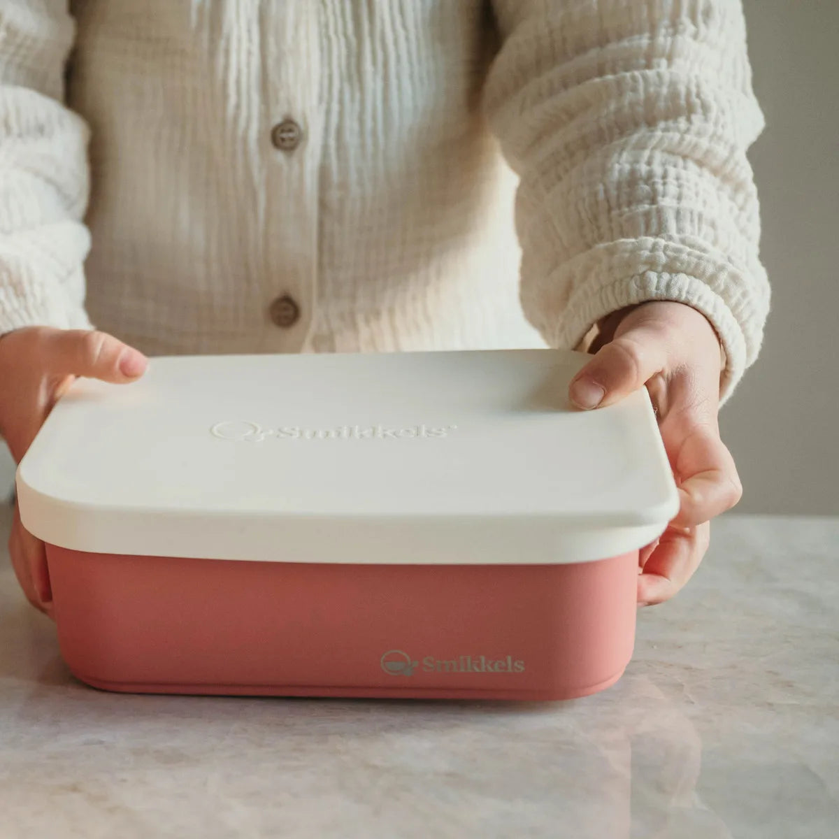 Meisje heeft roze rvs lunchbox met siliconen deksel in haar handen