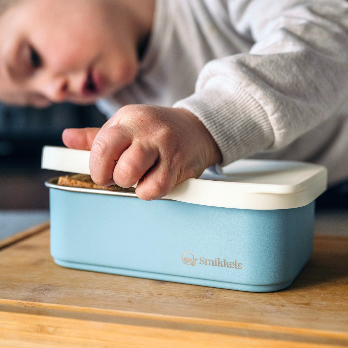 Jongetje opent blauwe rvs lunchbox met siliconen deksel