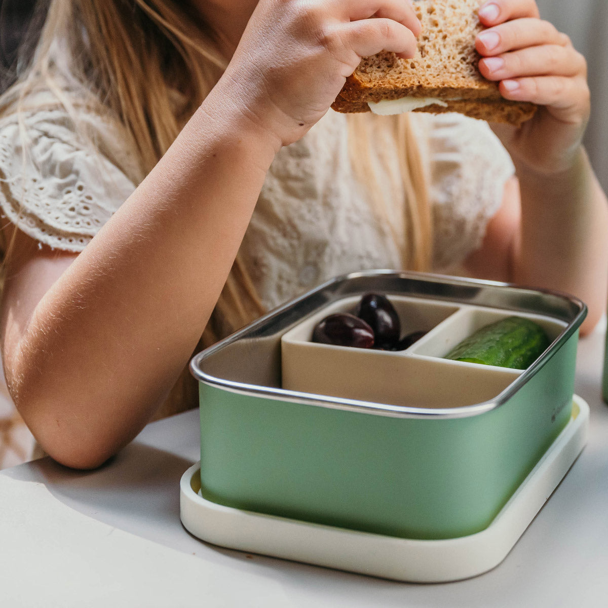 Meisje eet uit groene rvs lunchbox met siliconen deksel