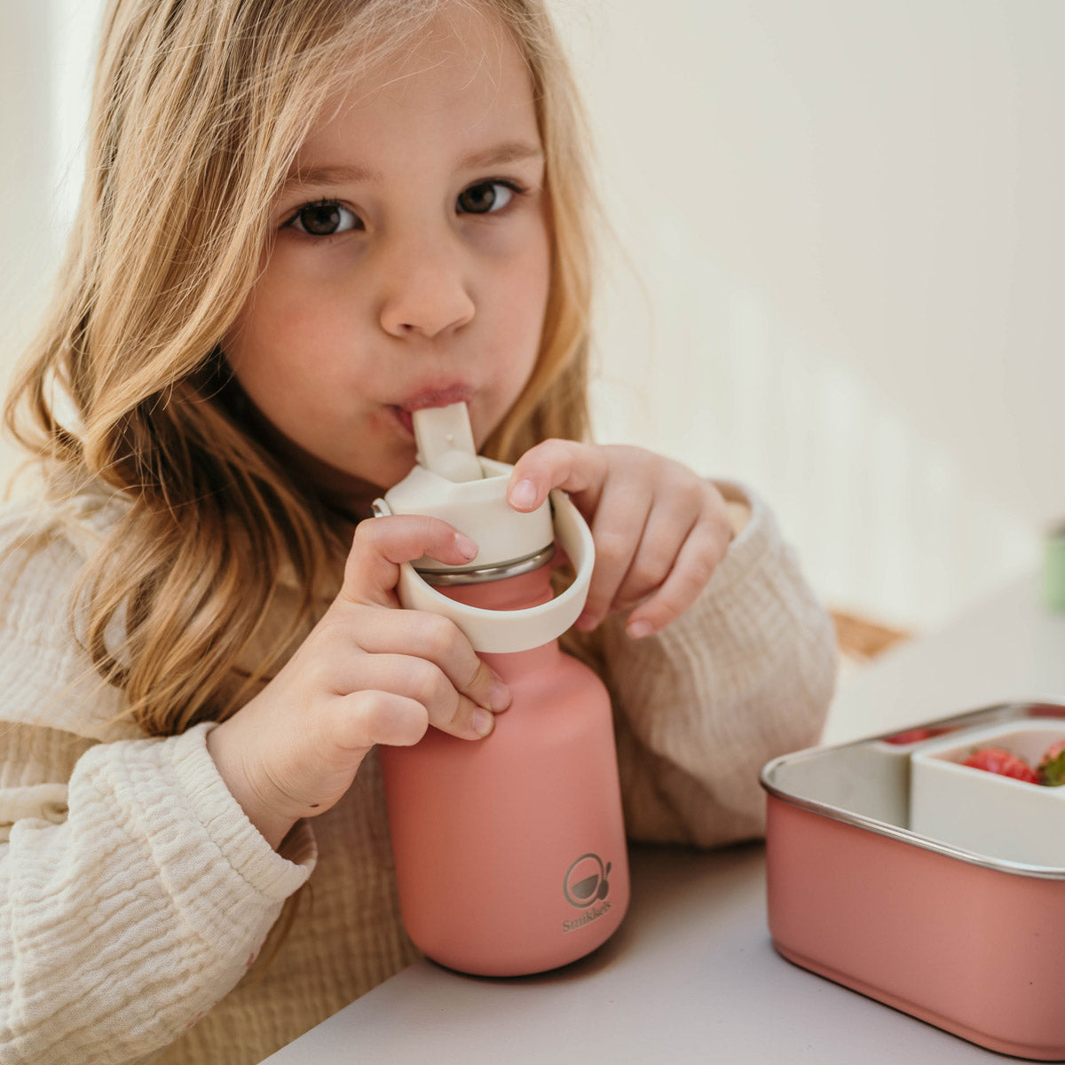 Meisje drinkt uit roze Smikkels drinkfles