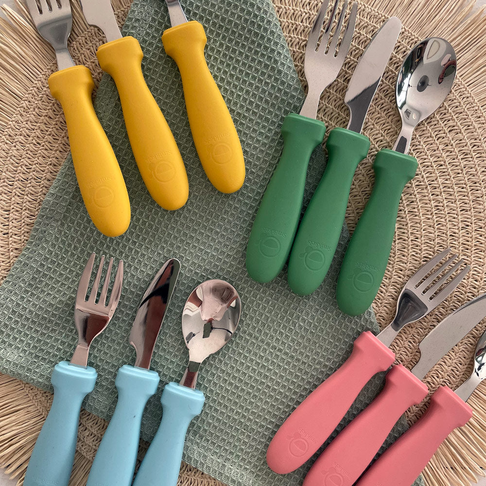 Sfeerbeeld kinderbestek van Smikkels in de kleuren groen, geel, blauw en roze.
