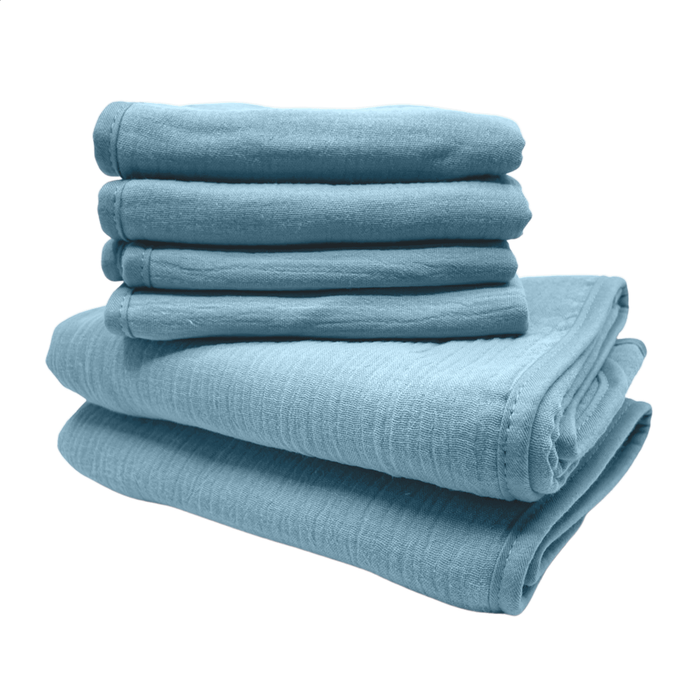 Een stapel van blauwe monddoekjes en babyhanddoeken van Smikkels met een grote rode strik er bij