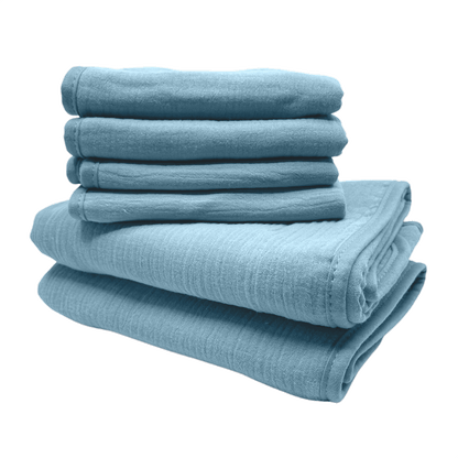 Een stapel van blauwe monddoekjes en babyhanddoeken van Smikkels met een grote rode strik er bij