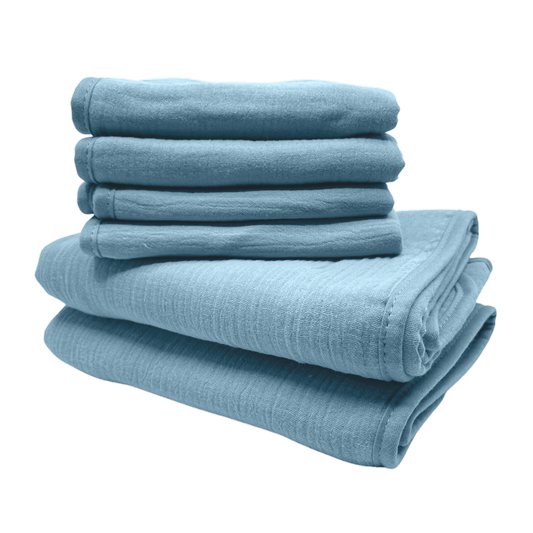 Een stapel van blauwe monddoekjes en babyhanddoeken van Smikkels met een grote rode strik er bij