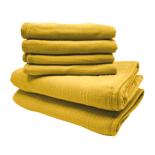 Een stapel van gele monddoekjes en babyhanddoeken van Smikkels met een grote rode strik er bij