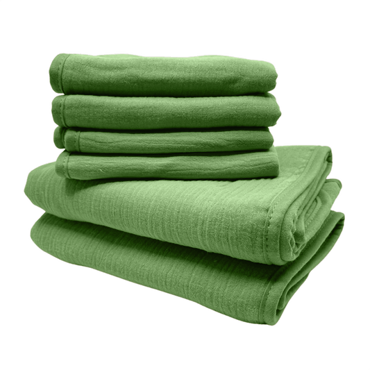 Een stapel van groene monddoekjes en babyhanddoeken van Smikkels met een grote rode strik er bij