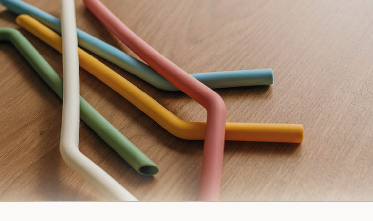 Herbruikbare siliconen rietjes in verschillende kleuren op een houten tafel