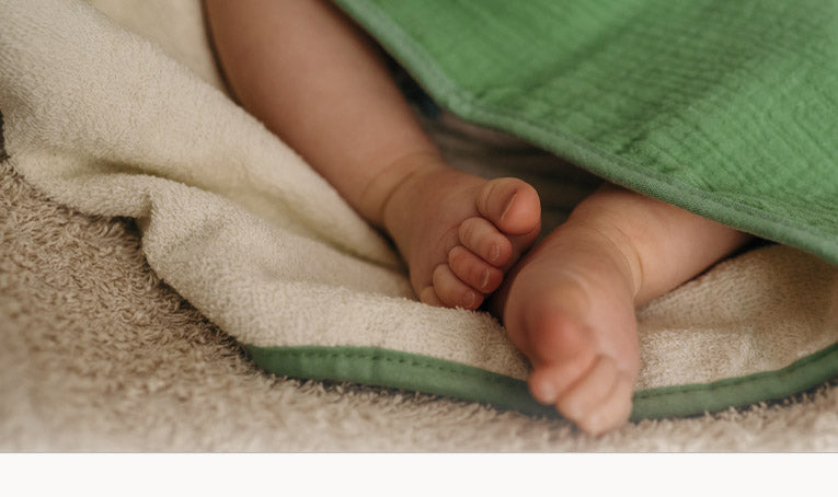 Twee beentjes van een baby gewikkeld in een groene babydoek van Smikkels