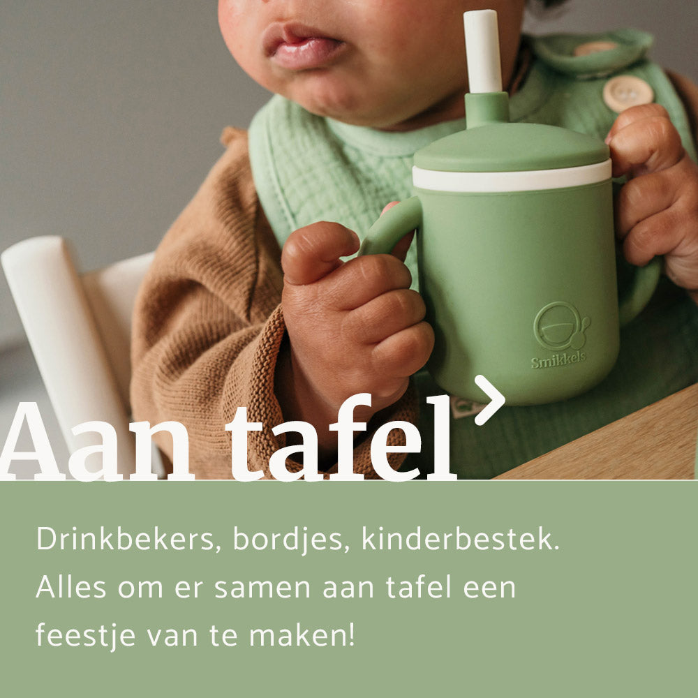 Baby houdt groene siliconen drinkbeker van Smikkels vast en draagt een groen katoenen slabbetje van Smikkels