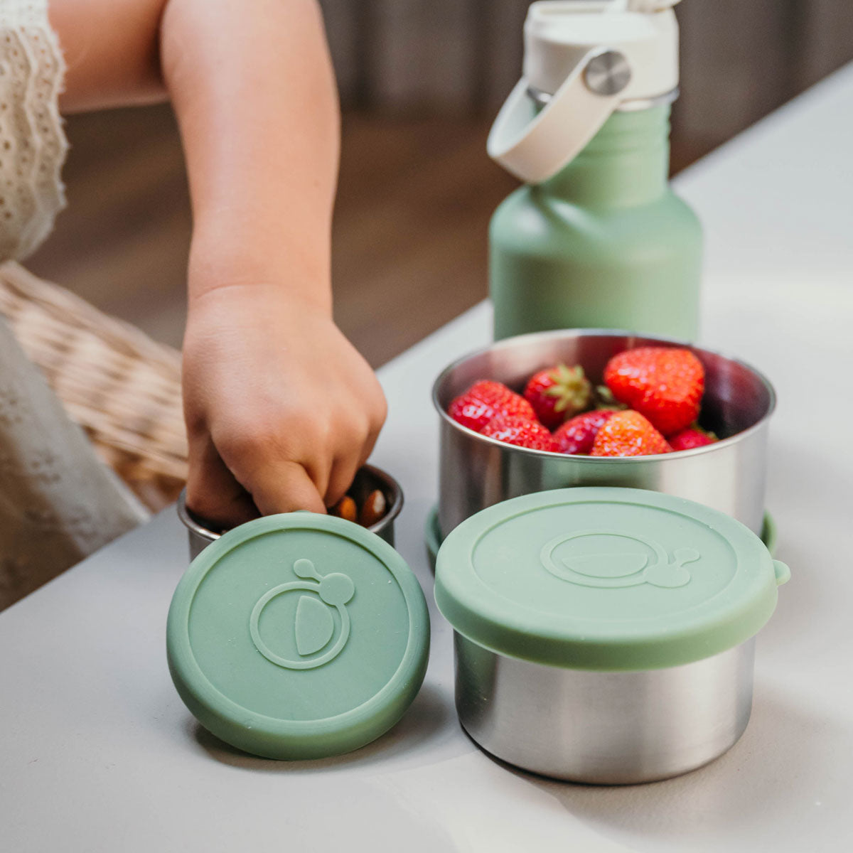 Meisje haalt nootjes uit groene fruit- en snackbakjes