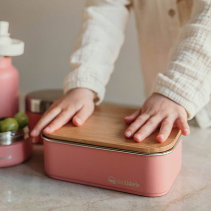 Kind drukt bamboe deksel op roze RVS Lunchbox van Smikkels