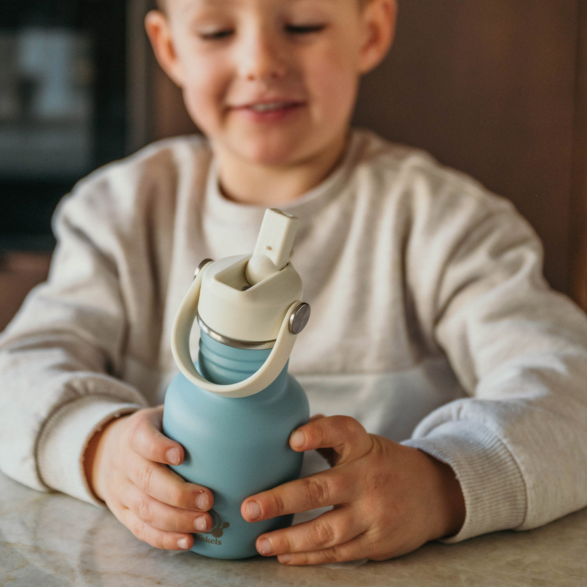 Jongetje houdt blauwe Smikkels drinkfles vast 