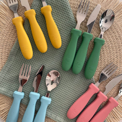 Sfeerbeeld kinderbestek van Smikkels in de kleuren groen, geel, blauw en roze.