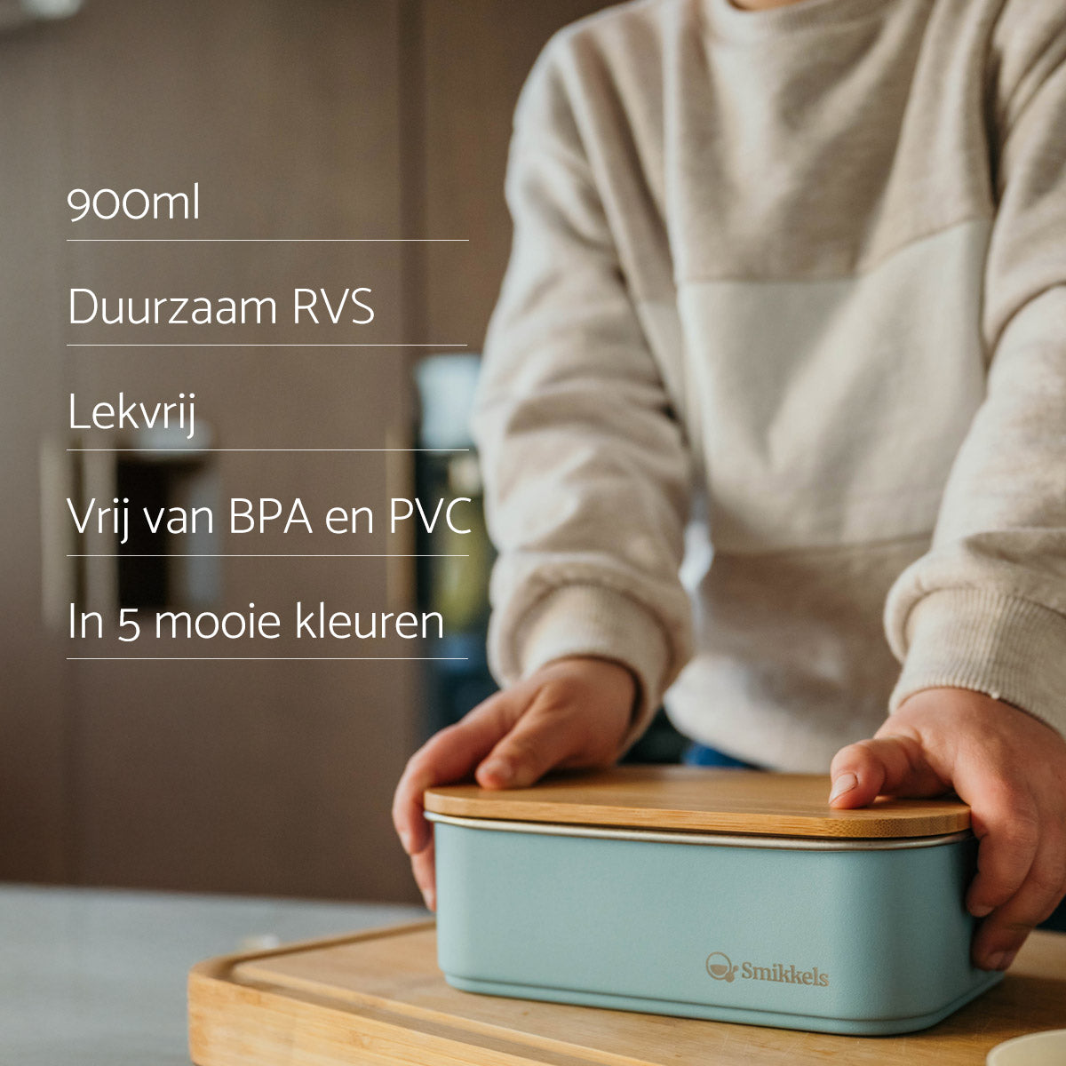 Jongen met beige trui druk een bamboe deksel op een blauwe RVS lunchbox van Smikkels