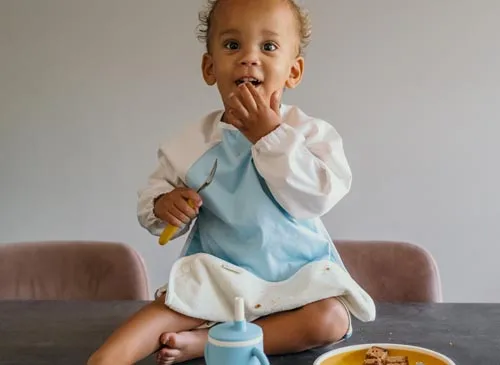 Baby met Smikkels slab met lange mouwen tijdens het eten